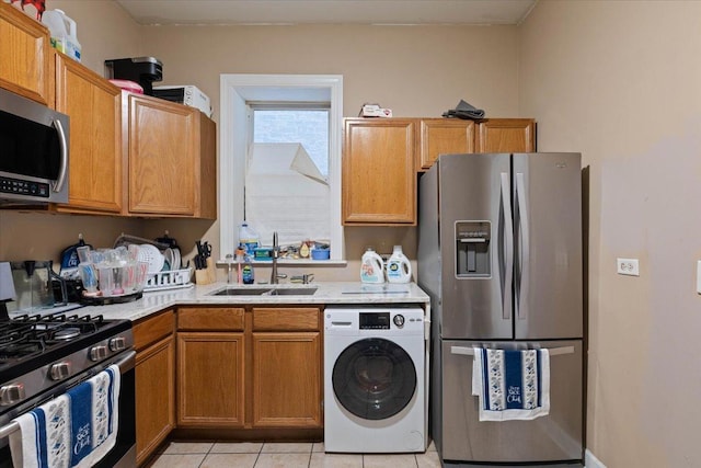 kitchen featuring appliances with stainless steel finishes, light tile patterned flooring, sink, and washer / clothes dryer