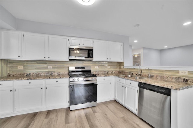 kitchen with sink, decorative backsplash, appliances with stainless steel finishes, light hardwood / wood-style floors, and white cabinetry