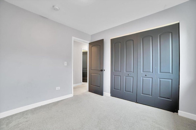 unfurnished bedroom with a closet and light colored carpet