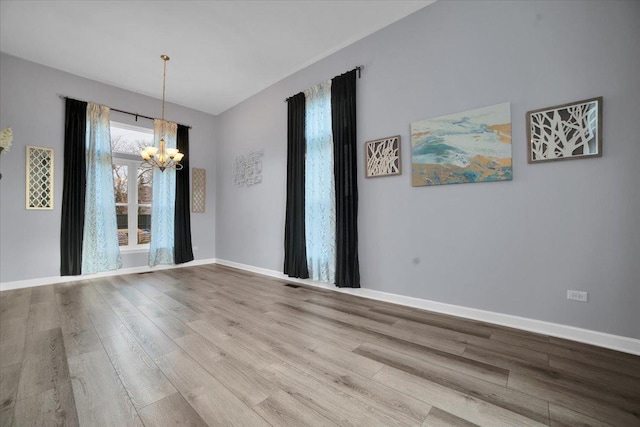 unfurnished dining area featuring hardwood / wood-style floors and a notable chandelier