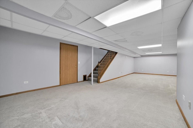 basement featuring light carpet and a paneled ceiling