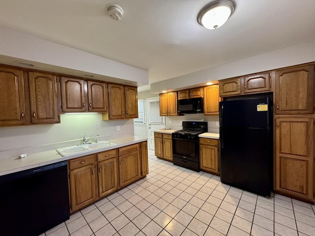 kitchen featuring sink, light tile patterned flooring, and black appliances