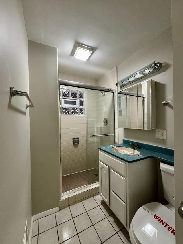 bathroom with tile patterned floors, a shower with door, vanity, and toilet