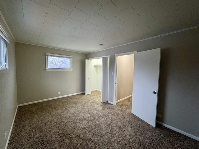 unfurnished bedroom featuring carpet, a walk in closet, crown molding, and a closet