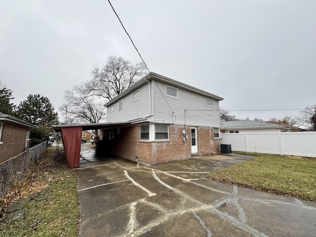 rear view of property featuring central AC and a carport