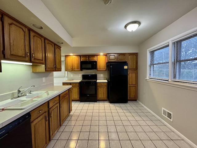 kitchen featuring sink, light tile patterned flooring, and black appliances