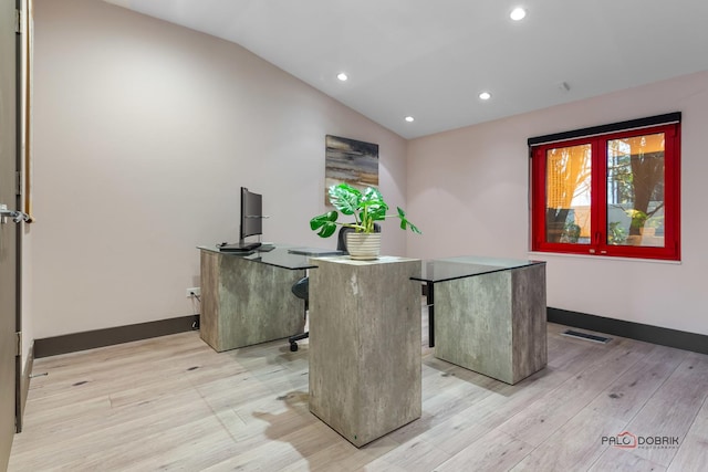 home office with light hardwood / wood-style floors and lofted ceiling