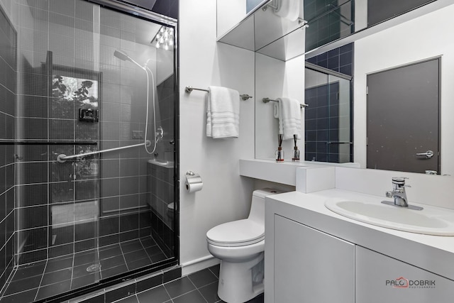 bathroom with tile patterned floors, vanity, toilet, and a shower with shower door