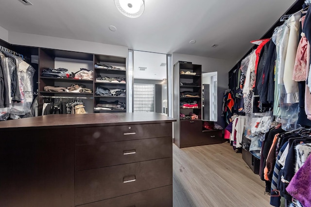 walk in closet with light hardwood / wood-style flooring