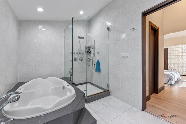 bathroom featuring hardwood / wood-style floors, plus walk in shower, and tile walls