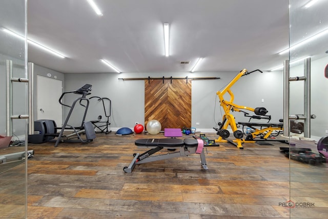 exercise room with a barn door and dark wood-type flooring