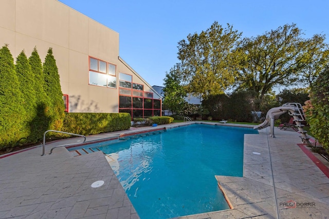 view of pool with a water slide and a patio