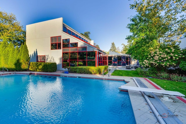 view of swimming pool with a lawn, a diving board, and a patio area