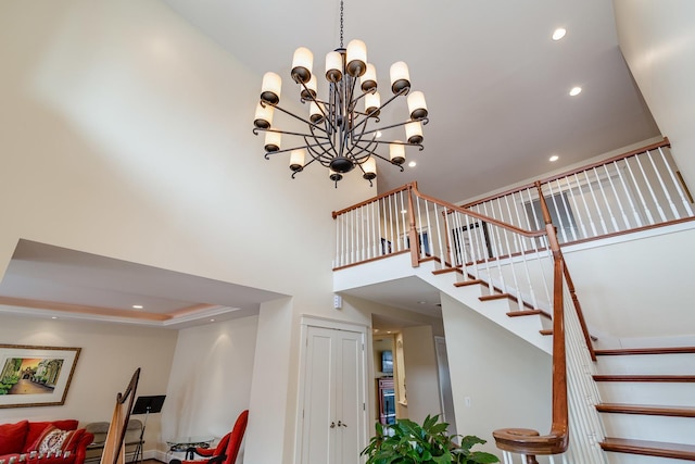 staircase featuring a high ceiling, a tray ceiling, and an inviting chandelier