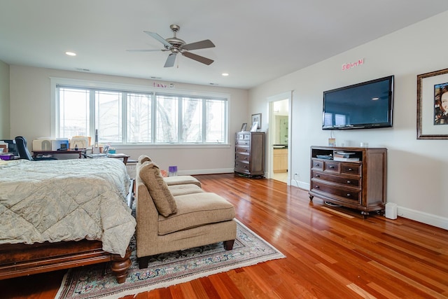 bedroom featuring multiple windows, ceiling fan, hardwood / wood-style floors, and ensuite bath