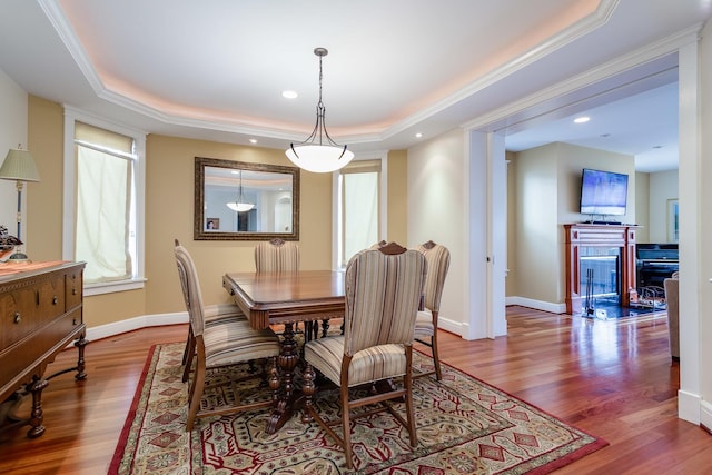 dining room with wood-type flooring, ornamental molding, and a tray ceiling