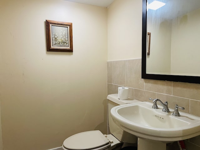 bathroom featuring backsplash, toilet, sink, and tile walls