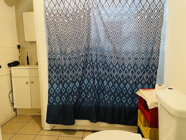 bathroom featuring tile patterned floors, walk in shower, vanity, tile walls, and toilet