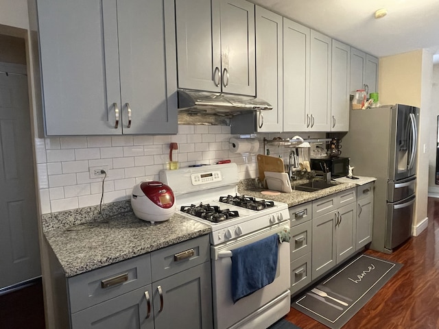 kitchen featuring light stone counters, dark hardwood / wood-style floors, stainless steel fridge, gray cabinets, and white range with gas cooktop