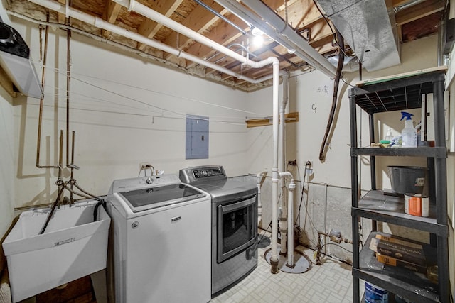 clothes washing area featuring washing machine and clothes dryer, electric panel, and sink