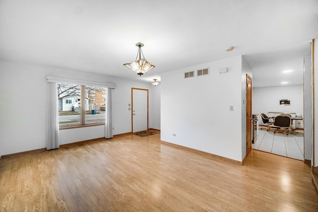 spare room with light hardwood / wood-style flooring and an inviting chandelier