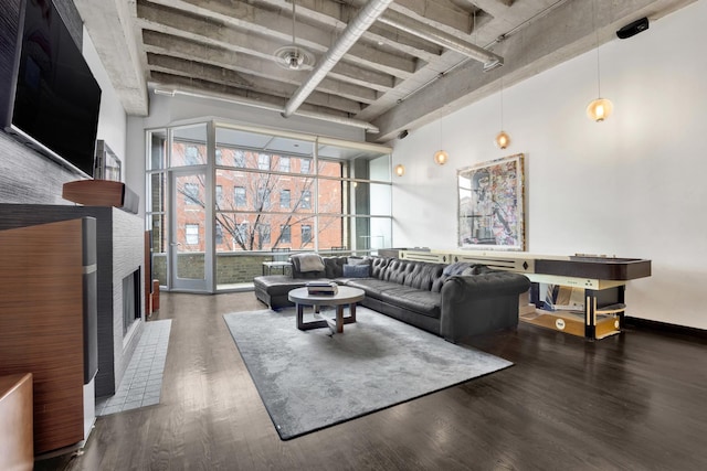 living room with a brick fireplace, a high ceiling, and dark hardwood / wood-style flooring