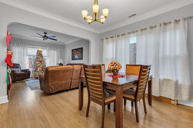 dining area featuring ornamental molding, ceiling fan with notable chandelier, and light wood-type flooring