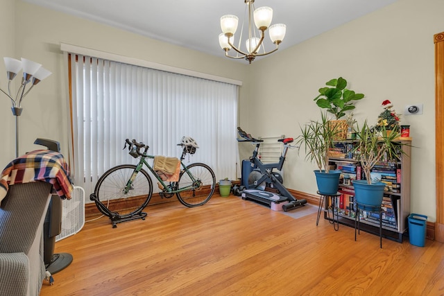 workout room featuring a chandelier and light hardwood / wood-style flooring