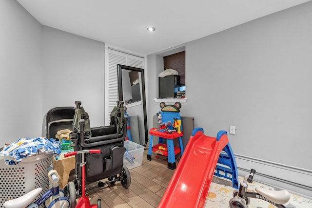 playroom featuring a baseboard heating unit and wood-type flooring