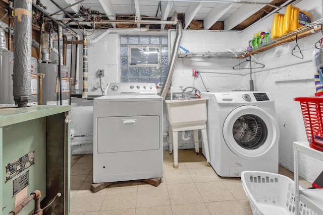 clothes washing area featuring sink, washer and clothes dryer, and light tile patterned flooring