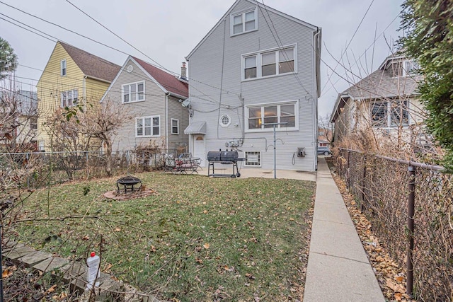 rear view of house featuring a yard, a patio, and a fire pit