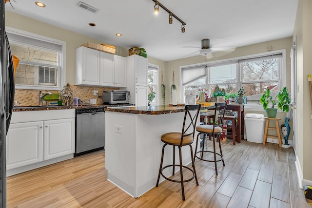 kitchen with light hardwood / wood-style flooring, white cabinetry, a center island, tasteful backsplash, and stainless steel dishwasher