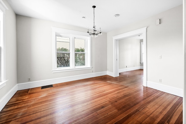 unfurnished dining area featuring a notable chandelier and dark hardwood / wood-style floors