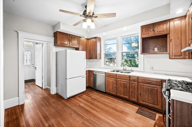 kitchen with stainless steel dishwasher, range with gas cooktop, sink, wood-type flooring, and white fridge