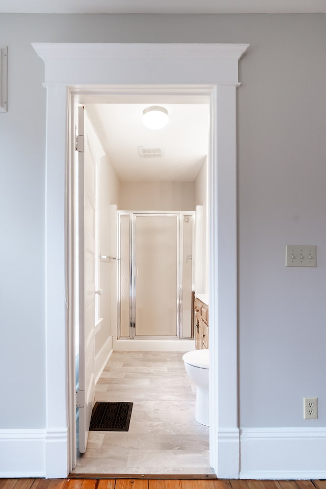 bathroom featuring toilet, vanity, a shower with shower door, and hardwood / wood-style flooring