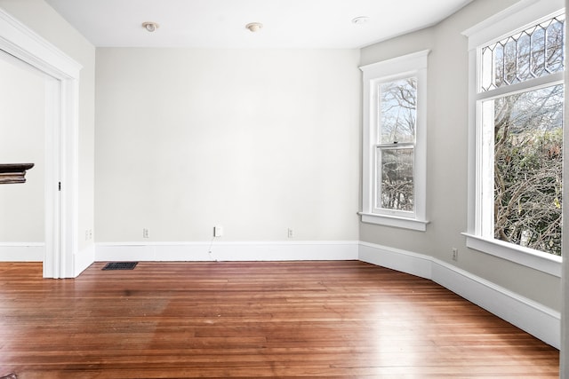 empty room with hardwood / wood-style flooring and plenty of natural light