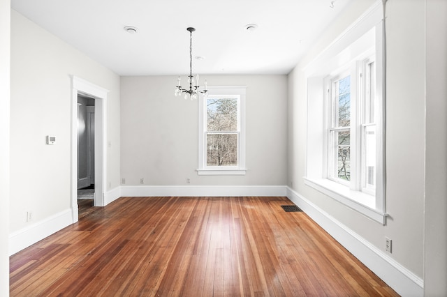 unfurnished dining area featuring a wealth of natural light, dark wood-type flooring, and a notable chandelier