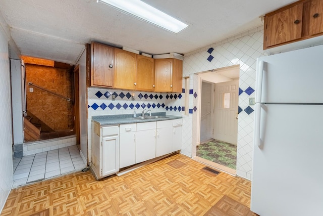 kitchen with white refrigerator, sink, a textured ceiling, and light parquet flooring