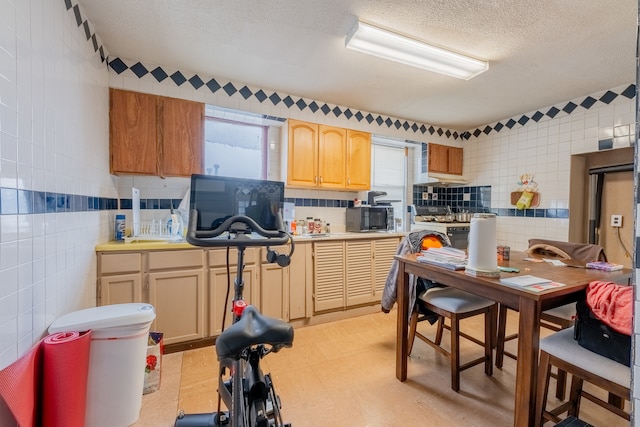 kitchen with gas stove, a textured ceiling, and tile walls