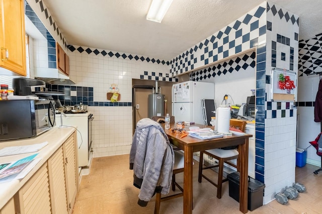 kitchen featuring water heater, white fridge, washer / dryer, light tile patterned flooring, and tile walls