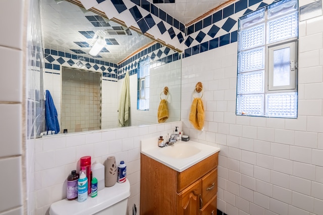 bathroom featuring vanity, tile walls, and toilet