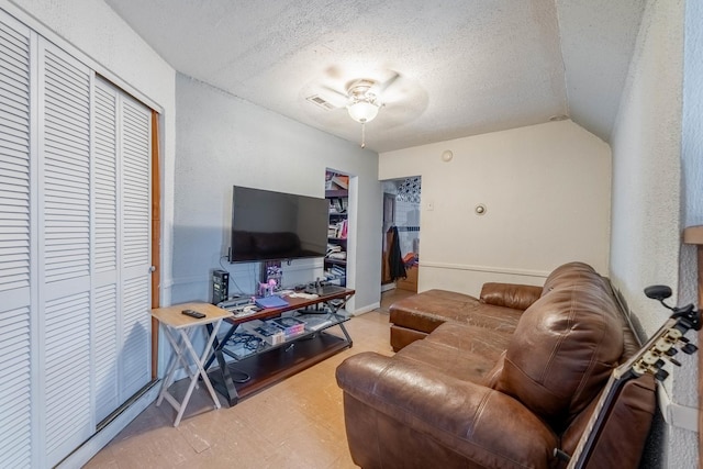 living room featuring ceiling fan, a textured ceiling, and vaulted ceiling