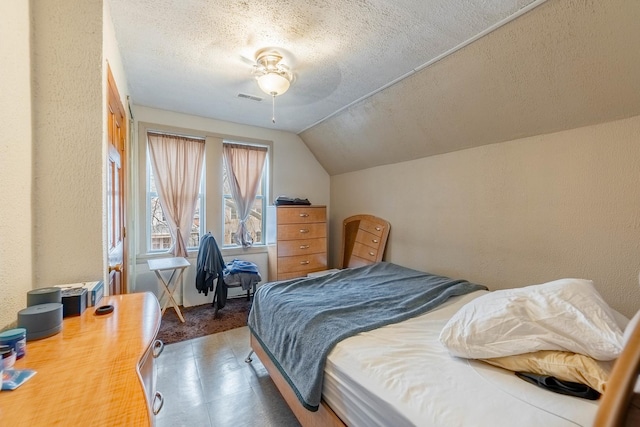 bedroom with a textured ceiling, vaulted ceiling, and ceiling fan