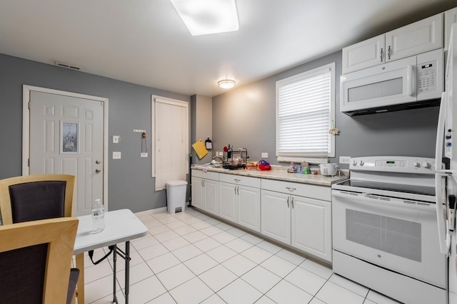 kitchen with white cabinetry, light tile patterned floors, and white appliances