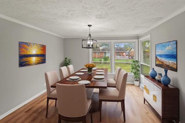 dining room featuring ornamental molding, light wood-type flooring, a textured ceiling, and a notable chandelier