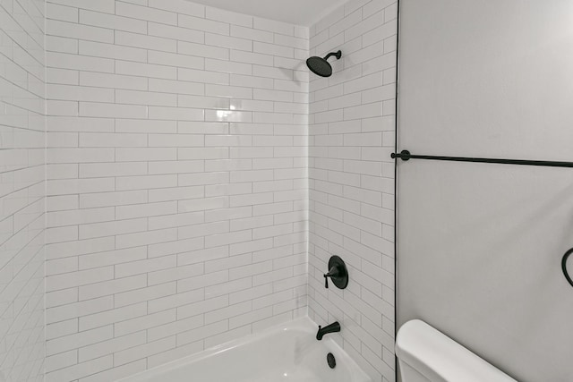 bathroom with tiled shower / bath combo and toilet