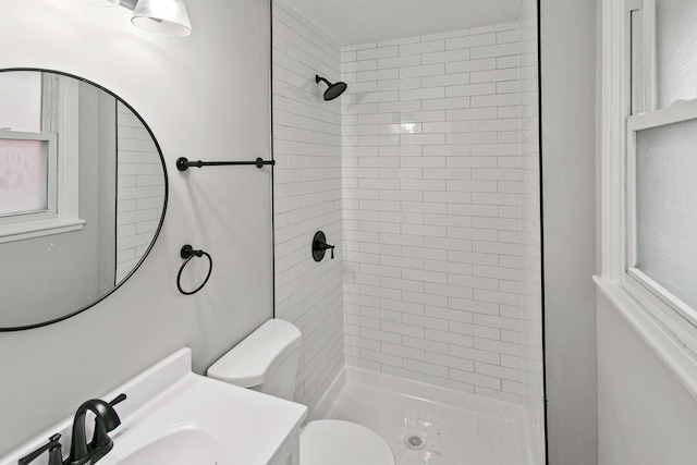 bathroom with a tile shower, vanity, and toilet