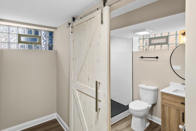 bathroom with a tile shower, hardwood / wood-style flooring, vanity, and toilet