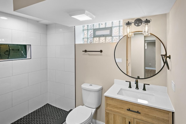 bathroom with tiled shower, vanity, and toilet