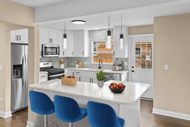 kitchen featuring white cabinetry, a center island, sink, hanging light fixtures, and appliances with stainless steel finishes